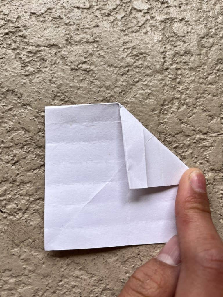 Flipped down and folding top corner down to meet middle crease. Making bottom point of the heart in the origami heart ring.