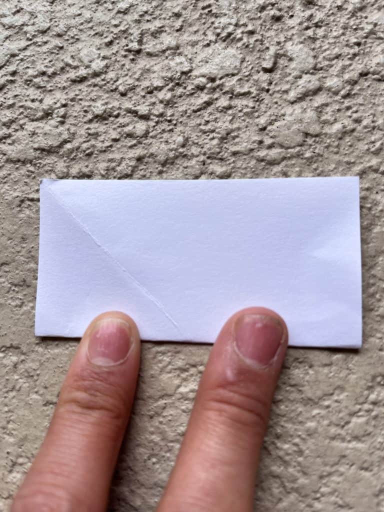 Folding square of paper in half. Starting ring of origami heart ring.