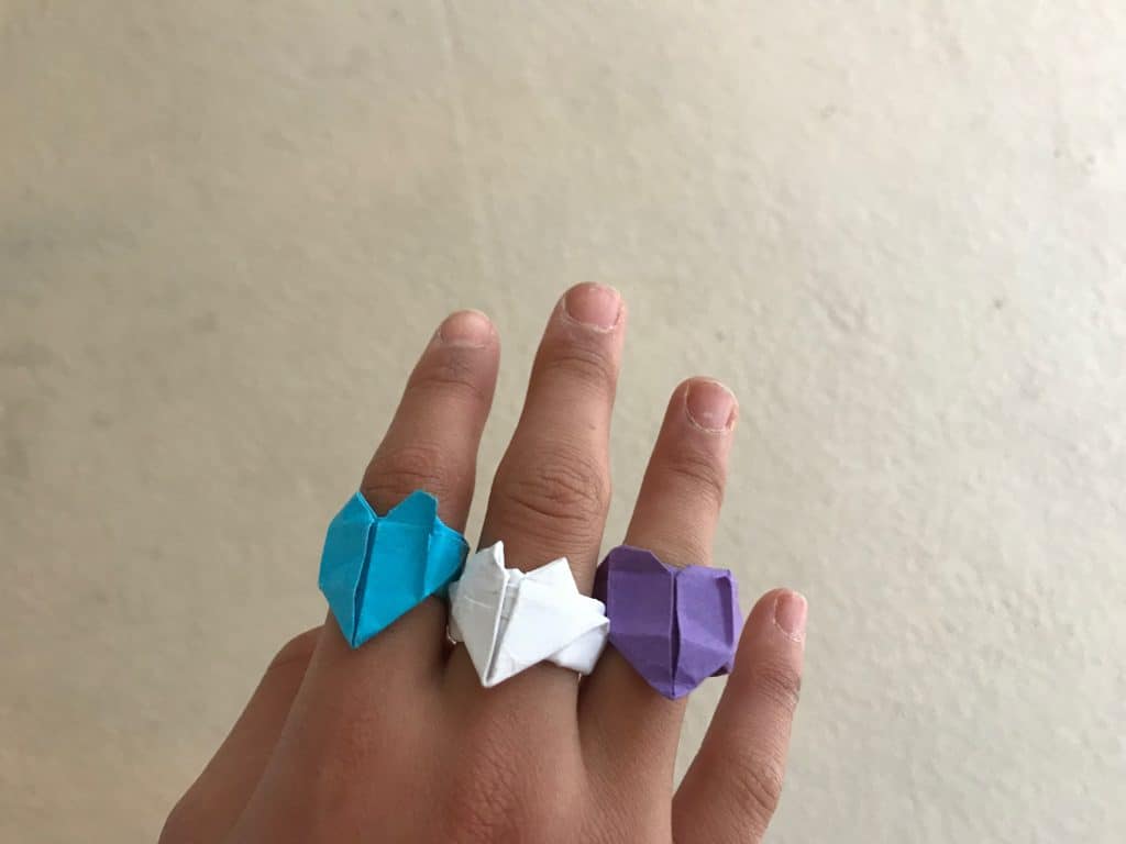 Teen girl's hand wearing origami heart rings.