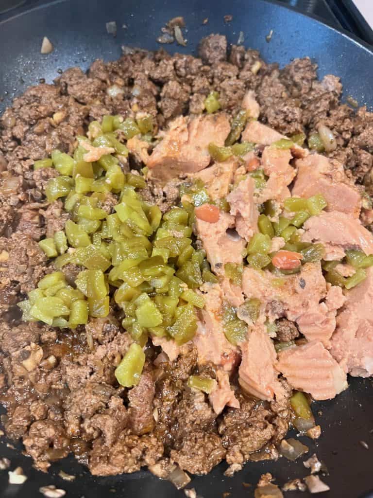 browned beef with chiles and refried beans in pan